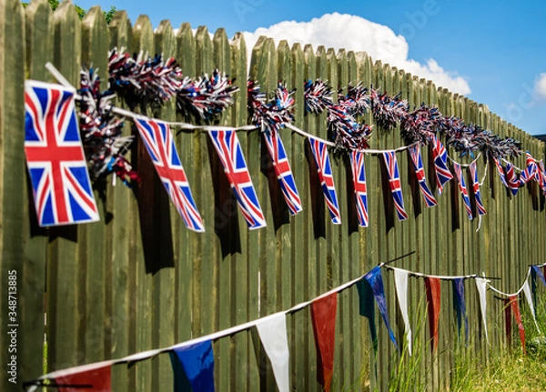 Obraz Union Jack bunting on a fence row, many flags in row on a string, triangular flags, front of garden VE day decorations in UK, memorial symbol of winning second world war