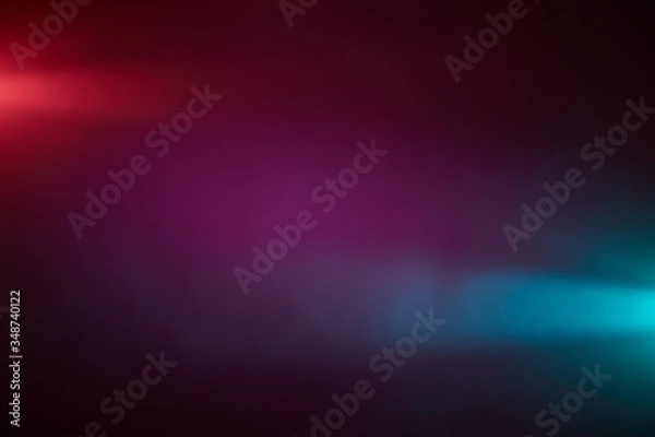Fototapeta Against a dark lilac background, piercing rays of light red and light blue