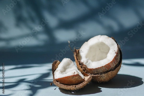 Fototapeta Half a coconut and pieces of coconut on a blue background.