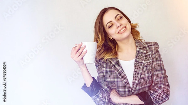 Fototapeta happy girl stands with a cup of coffee and dreams. beautiful girl in a checkered jacket is drinking coffee