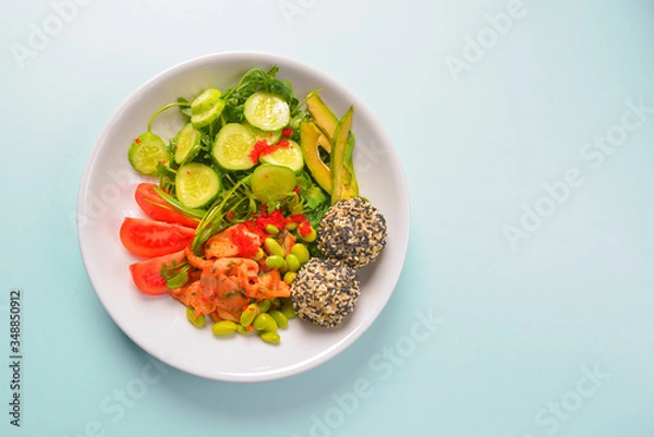 Fototapeta Fresh and organic vegetable salad with raw veggies - tomatoes, cucumbers, avocado. Flat lay, copy space banner.