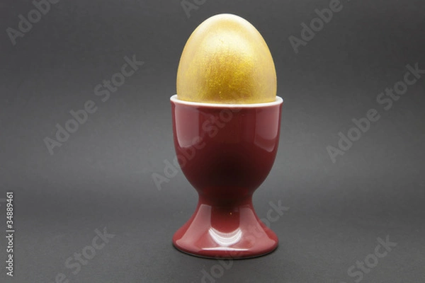Obraz Golden Egg in a red egg cup on a black background