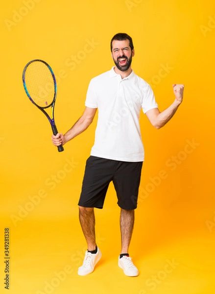 Fototapeta Full-length shot of man over isolated yellow background playing tennis and celebrating a victory