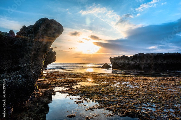 Fototapeta Amazingly beautiful long exposure sunset on the coast of Canggu, a resort village on the south coast of the Indonesian island of Bali. Rocks covered with seaweeds, reflection in the water.