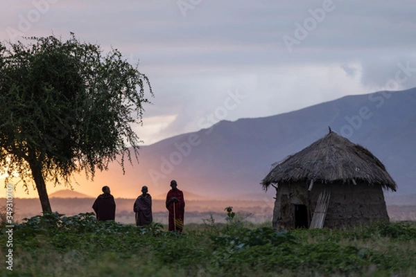 Fototapeta Arusha, Tanzania, 1 czerwca 2019 r. Grupa masajów w tej wiosce podczas wschodu słońca z pięknym kolorowym tłem