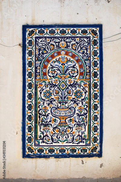Fototapeta Tunisian traditional mural in the form of ceramic tiles on a white cracked wall of an old house