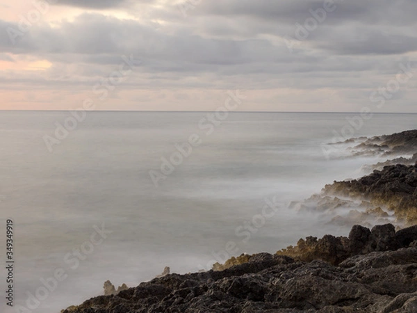 Fototapeta Sunset and waves crashing on the rocks