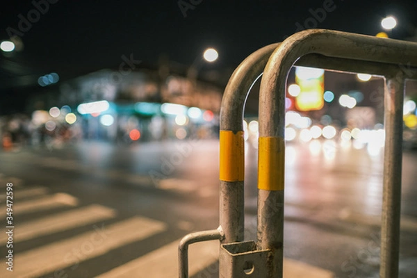 Fototapeta Iron fence isolated from traffic lights background in the night. Blur street background.