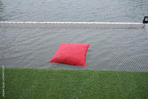 Fototapeta Red pillow placed on net over the river. Vacation net seat over the river.