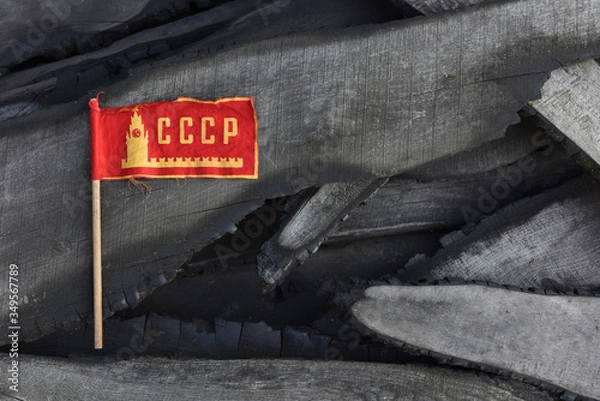 Fototapeta The old small flag of the Soviet Union on burnt boards. symbol of the Soviet Union. burnt past. concept
