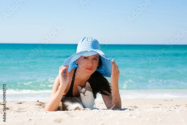 Obraz Dziewczyna na plaży z kotkiem i na sobie kapelusz