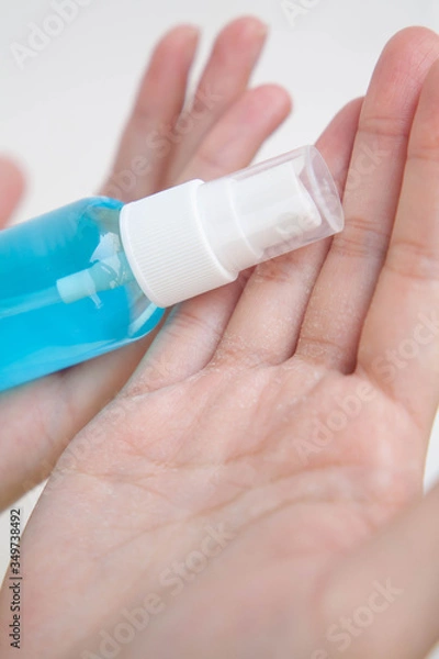 Fototapeta Closeup of cracked hands with alcohol spray bottle. Concept of using alcohol repeatedly during coronavirus pandemic crisis cause dry skin.