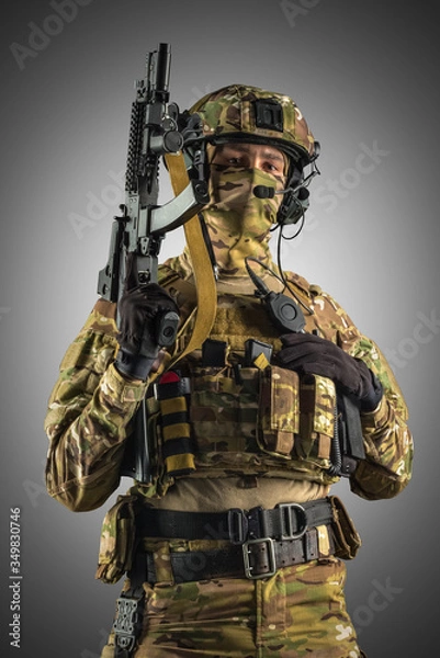 Fototapeta Soldier holding assault rifle. Uniform conforms to special services of the Russian Federation. Shot in studio. Isolated with clipping path on grey background