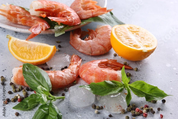 Fototapeta Seafood. Argentine prawns shrimps with lemon, basil, ice and spices  on a light grey background. Background image, copy space