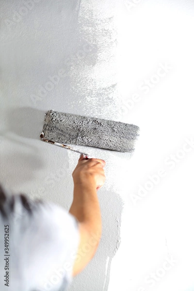 Obraz Human hand with large roller of paint begins to paint a white wall handicraft master painter training contrast color sample color test tool renovation gray silver craftsman