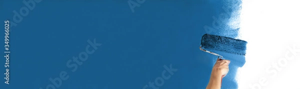 Obraz Human hand with large roller of paint begins to paint a white wall handicraft education contrast color sample color test tool renovation dark blue maritime children's room