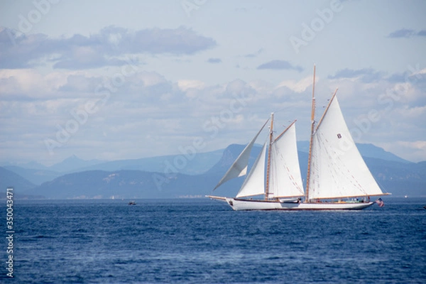 Fototapeta Sailboat on the ocean with mountains in the background