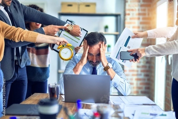 Fototapeta Group of business workers working together. Partners stressing one of them at the office