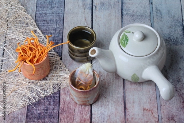 Obraz Golden cordyceps mushroom in cup ,herbal tea bag of  golden cordyceps militaris and a cup of tea served on wood