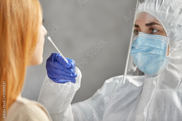 Fototapeta medicine, health and virus concept - doctor or healthcare worker in protective wear, medical mask and face shield making coronavirus test and taking sample from patient