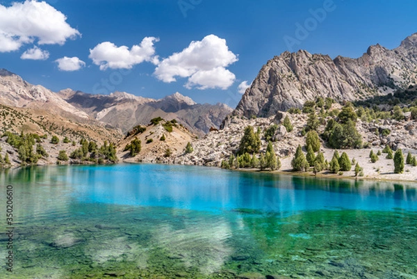 Fototapeta The beautiful mountain trekking road with clear blue sky and rocky hills and the view of Alaudin lake in Fann mountains in Tajikistan