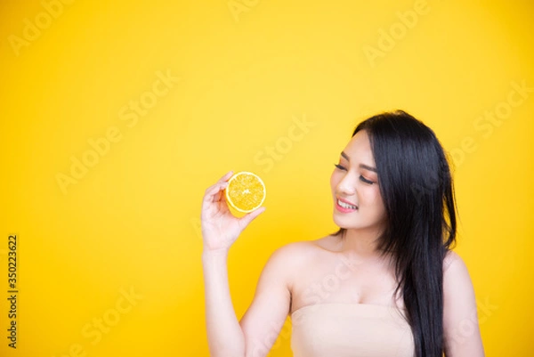 Fototapeta Beautiful Asian women smile happyness holding fresh orange slide with a yellow background.Squeeze Fresh oranges healthy fruits that are vitamin C.