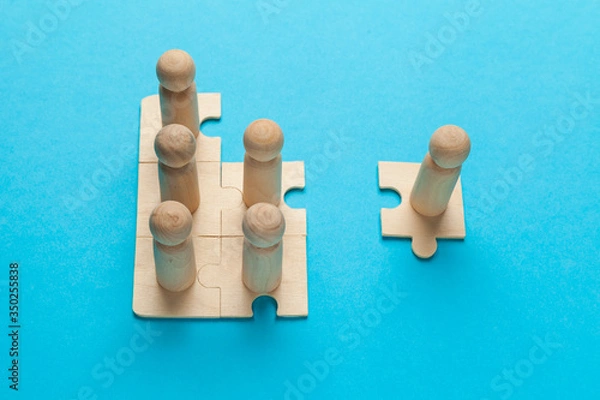 Fototapeta Wooden figures on puzzles on blue background as a symbol of team building. Organization group people in business. Cooperation and partnership.