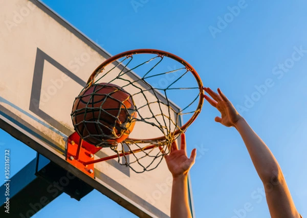 Fototapeta Street basketball slam dunk competition. Close up of ball falling into the hoop. Urban youth game. Concept of success, scoring points and winning