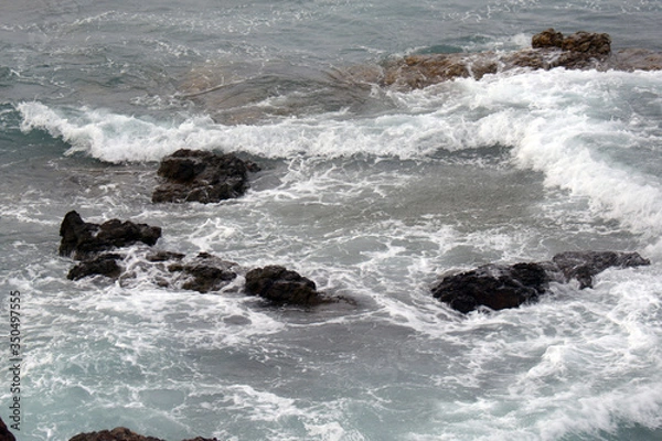 Fototapeta small waves at the stones, crashing with foam