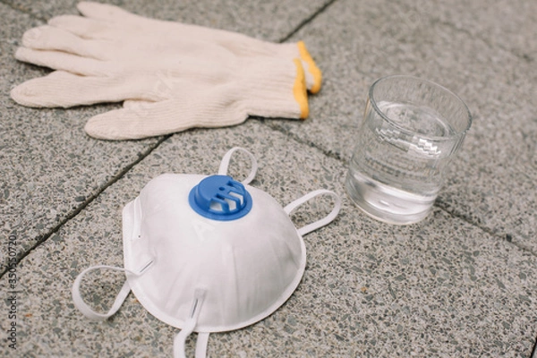 Obraz Mask, gloves are lying on the grey table background. Glass of water is standing on the grey background. Safety.