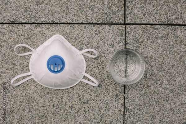 Obraz Mask, gloves are lying on the grey table background. Glass of water is standing on the grey background. Safety.