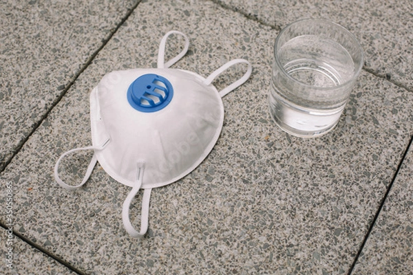 Obraz Mask, gloves are lying on the grey table background. Glass of water is standing on the grey background. Safety.