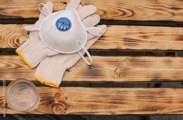 Obraz Mask, gloves are lying on the wooden table background. Glass of water is standing on the wooden background. Safety.