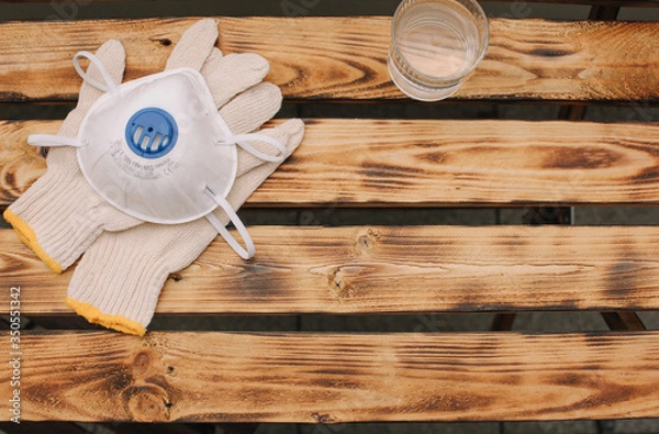 Obraz Mask, gloves are lying on the wooden table background. Glass of water is standing on the wooden background. Safety.