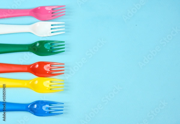 Fototapeta Multicolored plastic dishes on a blue background. The concept of environmental pollution by plastic, ecolog place for text, flat lay