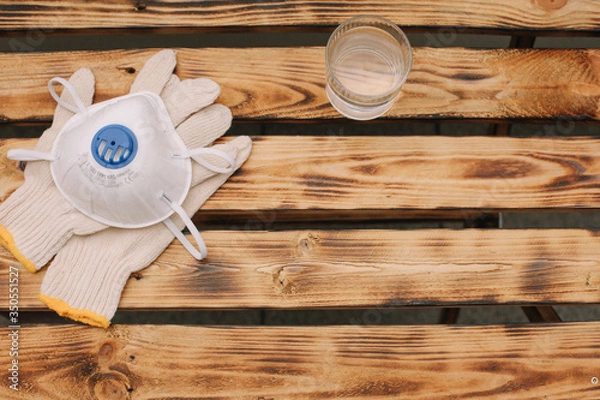 Obraz Mask, gloves are lying on the wooden table background. Glass of water is standing on the wooden background. Safety.