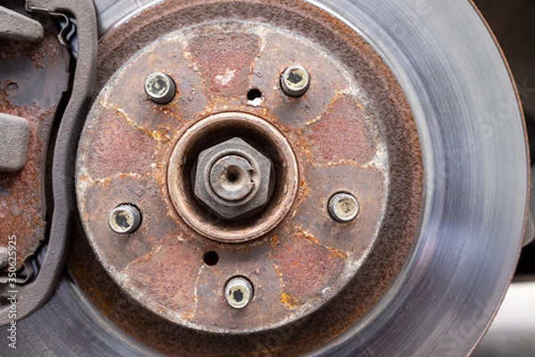 Fototapeta Rusty back car wheel hub with five bolts and brake disc at tire shop. Car without a wheel while replacing on the tire service center. Closeup view
