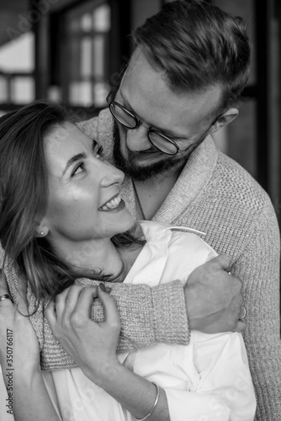 Fototapeta Beautiful young couple at home. Hugging, kissing and enjoying spending time together in the kitchen. Concept of good relations.