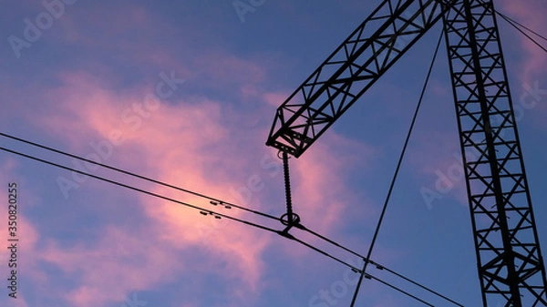 Fototapeta Silhouette of high voltage electric tower at beautiful sunset with dramatic clouds