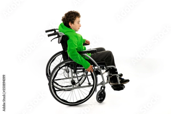 Fototapeta Little boy in wheelchair on white background , boy is sitting in a wheelchair on a white background. Hospital patient with disability