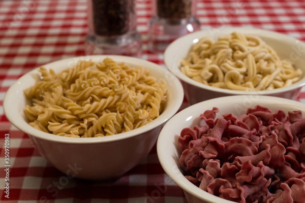 Fototapeta Raw italian pasta in a red and white towel background top view