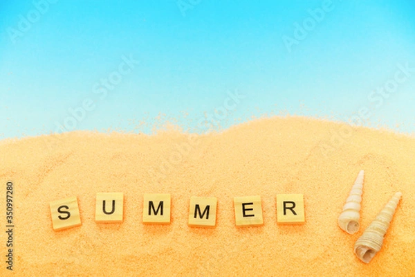 Fototapeta Summer vacation background, sand, shells, words Summer. Concept of a summer vacation on the beach with a blue copy of the space