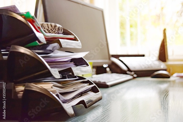 Fototapeta Business documents on an office desk with a printer and computer as a business concept of a workspace. With cloud exposure