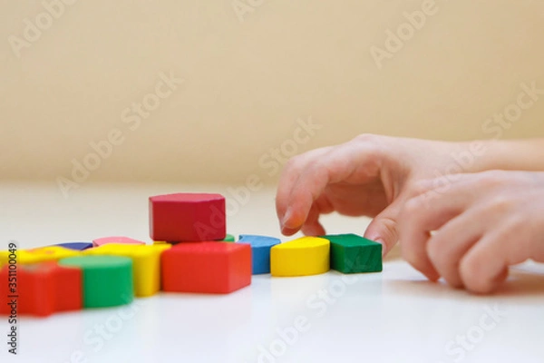 Fototapeta the child plays with colored figures. Details of the toy in the hands. Concept of development of fine motor skills, educational games, childhood, IVF, children's day, kindergarten. copy space