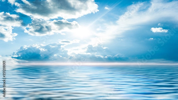 Fototapeta Sea landscape, sea surface. Blue sky, clouds, sunlight, rays. Empty natural scene in the open air. Blurred abstract background. Background of a sea landscape. Blue sky with clouds over the sea. 