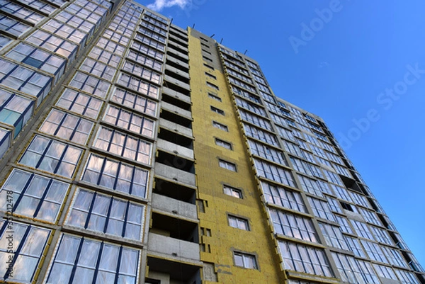Fototapeta Modern residential buildings architecture background. Mineral wool insulation of the facade building on construction site. Thermal protection of house. Installation double-glazed windows with frames