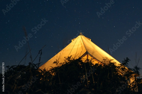Obraz Glamping illuminated from the inside against a starry sky on a summer night. Camping and outdoor concept.