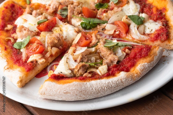 Fototapeta Fette di deliziosa pizza con tonno, cipolla, mozzarella e pomodorini 