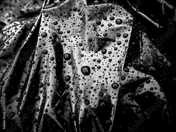 Fototapeta Drops on a black bag. Abstract background. Garbage bag in the water. Body bag. Rain on the street.