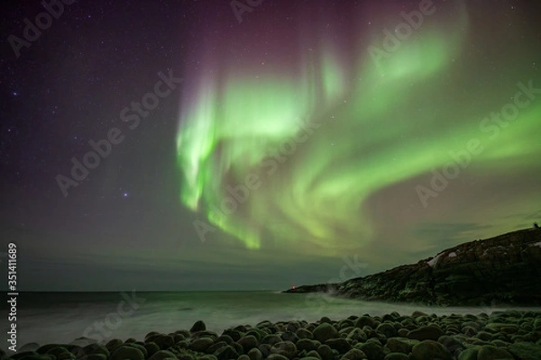 Obraz colorful northern light aurora borealis with purple, red, green and blu flames over the sky in iceland in a beach in